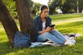 Beautiful young woman student in the park listening music with headphones using mobile phone. Royalty Free Stock Photo