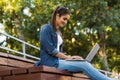 Amazing young beautiful woman sitting outdoors using laptop computer. Royalty Free Stock Photo