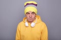 Image of angry aggressive Caucasian hipster man wearing beanie hat and yellow casual hoodie, arguing with somebody, looking at