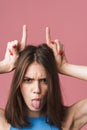 Image of angry brunette woman holding hands on her head like devil horns Royalty Free Stock Photo