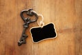 Image of antique key and empty blackboard tag over old wooden table. Royalty Free Stock Photo