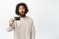 Image of arab man showing credit card, making surprised face expression, white background Royalty Free Stock Photo