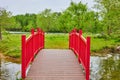 Arching red walking bridge with tiny stream and small island with grazing flock of Canadian geese Royalty Free Stock Photo