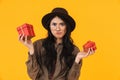 Image of asian woman hesitating while holding two birthday present boxes