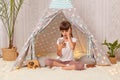 Image of astonished shocked little girl with braids wearing white t shirt posing in peetee tent, child using cell phone, sees