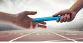 Image of athlete's hands passing relay baton over racing track in sports stadium Royalty Free Stock Photo