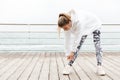 Image of athletic young woman bending and stretching her body while doing workout near seaside Royalty Free Stock Photo