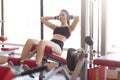 Image of attractive athltic woman pumps press on simulator in sports gym, tones muscles, liffting upper body, develop definition