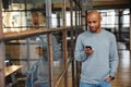 Image of attractive bald african american man holding cellphone in office Royalty Free Stock Photo