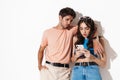 Image of attractive confused couple hugging while using cellphone