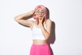 Image of attractive glamour girl in pink wig, bright halloween makeup, standing over white background with peace sign