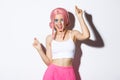 Image of attractive party girl with pink wig and bright makeup, having fun and celebrating holiday, dancing happy over