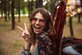 Image of attractive woman 20s, wearing stylish accessories smiling while resting in forest camp Royalty Free Stock Photo