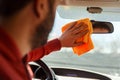 Image from back of man with orange rag washing mirror of car Royalty Free Stock Photo