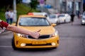 Image from back of woman with outstretched hand stopping taxi in afternoon on blurred background.