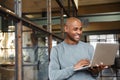 Image of bald african american man holding laptop while working in office Royalty Free Stock Photo