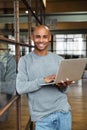 Image of bald african american man holding laptop while working in office Royalty Free Stock Photo