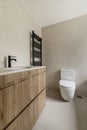 Image of the bathroom with cream-colored tiles, matching countertop, wooden cabinet with drawers and matching black taps with Royalty Free Stock Photo