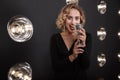 Image of beautiful artist woman in elegant dress singing into microphone