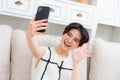 Image of beautiful asian woman laughing and showing peace sign while taking selfie photo on cellphone Royalty Free Stock Photo