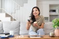 Image of a beautiful asian woman searching channel with remote control to watch tv while sitting on sofa at home Royalty Free Stock Photo