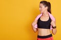 Image of beautiful athletic woman with rosy towel on shoulders posing isolated over yellow background, sporty female feels tired