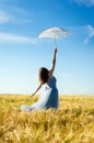 Image of beautiful blond young woman wearing long blue ball dress and holding white lace umbrella leaning up on wheat field Royalty Free Stock Photo