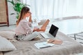 Image of beautiful concentrated young woman indoors at home using laptop computer sit in bed Royalty Free Stock Photo