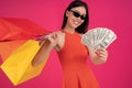 Image of a beautiful excited happy asian woman posing isolated over pink wall background holding shopping bags and money. dressed Royalty Free Stock Photo