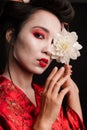 Image of beautiful geisha woman in japanese kimono holding flower