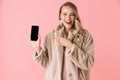 Beautiful happy young pretty woman posing isolated over pink wall background showing display of mobile phone Royalty Free Stock Photo