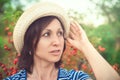 Image of beautiful middle-aged woman wearing straw hat looking aside while walking in summer park Royalty Free Stock Photo