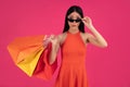 Image of a beautiful shocked young brunette asian woman posing isolated over pink wall background holding shopping bags Royalty Free Stock Photo