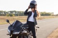 Image of beautiful slender young risk taker sitting on her motorcycle, having trip on her vehicle, fond of extreme activities,