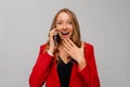 Image of beautiful smiling blonde woman talking on cellphone and laughing, having business call on mobile phone, standing in red Royalty Free Stock Photo