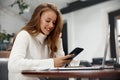 Image of beautiful woman smiling and using cellphone. Girl working with laptop Royalty Free Stock Photo