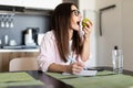 Beautiful young student girl with apple indoors using laptop computer writing notes Royalty Free Stock Photo