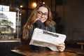 Beautiful young woman sitting in cafe indoors reading newspaper Royalty Free Stock Photo