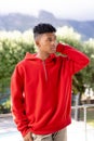 Image of biracial man in red hooded top with copyspace over trees in background Royalty Free Stock Photo