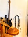 A black bass guitar hanging up in a studio with cymbals