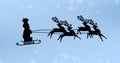 Image of black silhouette of stack of presents on sleigh being pulled by reindeer with snow fall