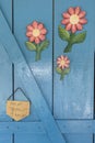 Image of blue entrance door decorated with wooden flowers