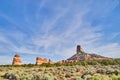 Blue sky with landscape of red rock pillars in green field of desert