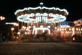 Blur street with festive lights and carousel in night time. Blur bokeh light defocused background Royalty Free Stock Photo