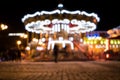 blur street with festive lights and carousel in night time. Blur bokeh light defocused background Royalty Free Stock Photo