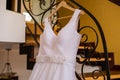 Image of the bodice of a white wedding dress on a wooden hanger