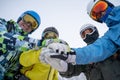 Image from bottom of four happy snowboarders in helmet doing handshake