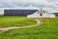 Bourbon rackhouse warehouse for Jim Beam under cloudy skies and with green grass and a trail