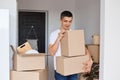 Image of brunette happy man wearing white t shirt standing with cardboard box, male holding carton parcels with personal Royalty Free Stock Photo