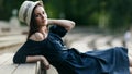 Image of brunette in hat sitting on wooden bench